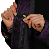 Close-up of hands zipping a dark jacket with a purple pattern